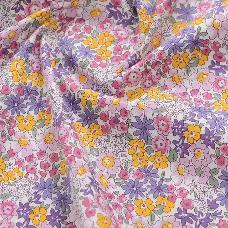 Popeline de coton à fleurs au mètre de Longan Craft France : tissu doux 100% coton, imprimé floral aux petites fleurs roses, jaunes et violettes sur fond clair, idéal pour quilting, nappes, robes ou chemises.