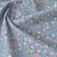 Popeline de coton à fleurs au mètre de Longan Craft France : 100% coton, doux, imprimé floral rose, blanc et jaune sur fond bleu clair avec feuillage vert. Idéal pour quilting, nappes, robes et chemises.
