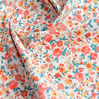 Un gros plan de Popeline de coton à fleurs au mètre de Longan Craft France montre un tissu 100 % coton avec un imprimé floral lumineux, idéal pour le quilting, les nappes, les robes et les chemises. La matière douce est légèrement drapée et parfaite pour les projets créatifs.
