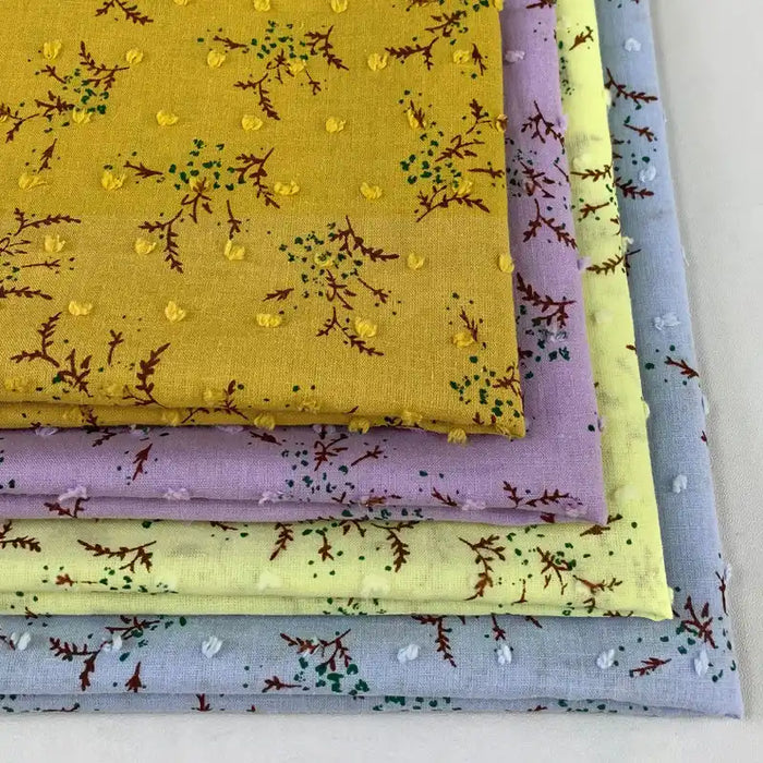 Quatre tissus en voile jacquard plumetis de Longan Craft France, de couleur jaune, lavande, jaune clair et bleu clair, présentent chacun des imprimés floraux avec des branches rouges et des grappes vertes, idéaux pour les robes d'été.