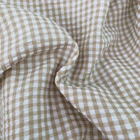Gros plan sur le Seersucker vichy au mètre de Longan Craft France : un seersucker à carreaux beige et blanc, légèrement froissé, qui présente des petits carrés issus de rayures verticales et horizontales régulièrement espacées.