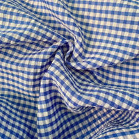 Gros plan sur le seersucker vichy au mètre de Longan Craft France : tissu léger et froissé en seersucker avec un petit motif de carreaux bleus et blancs et des plis visibles.