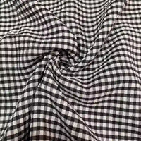 Gros plan sur le Seersucker vichy au mètre de Longan Craft France, qui présente des carreaux noirs et blancs avec une texture ridée et légère dans ce tissu seersucker froncé.