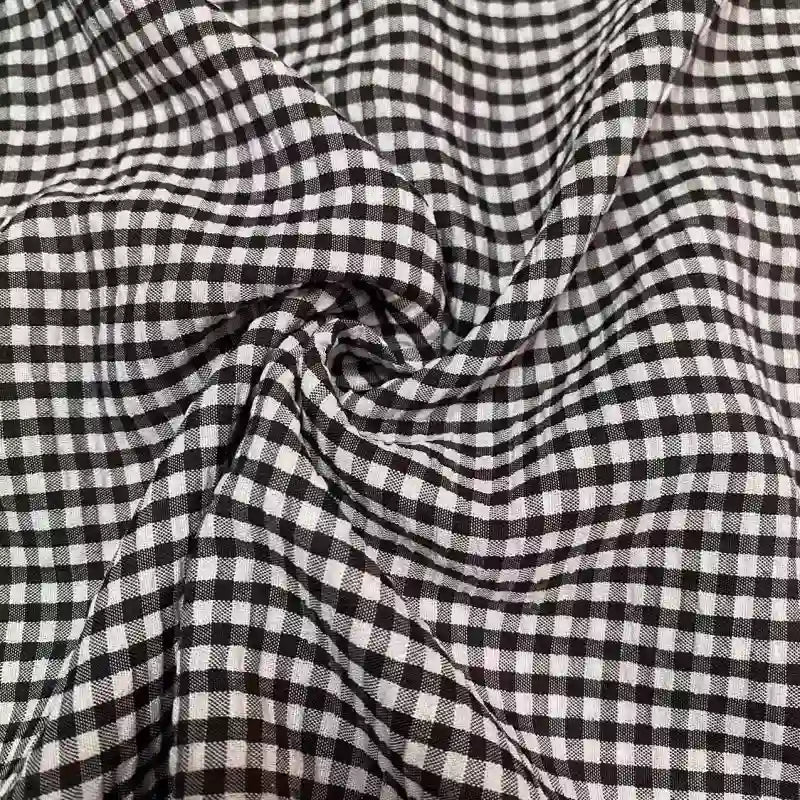 Gros plan sur le Seersucker vichy au mètre de Longan Craft France, qui présente des carreaux noirs et blancs avec une texture ridée et légère dans ce tissu seersucker froncé.