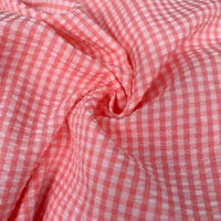 Un gros plan du Seersucker vichy au mètre de Longan Craft France montre ses carreaux roses et blancs, sa texture froissée et ses plis de seersucker doux - parfait pour les projets de couture nécessitant de la matière seersucker froncée à carreaux.