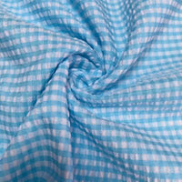 Gros plan sur le Seersucker vichy au mètre de Longan Craft France, un seersucker à carreaux bleu clair et blanc à petits carreaux, torsadé pour mettre en valeur sa texture froncée et son toucher léger et doux.
