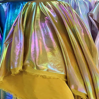 Gros plan sur le Lamé irisé au mètre de Longan Craft France, un tissu lamé métallique en polyester brillant avec reflets arc-en-ciel chatoyants et bord brut, idéal pour costumes de scène et performances.