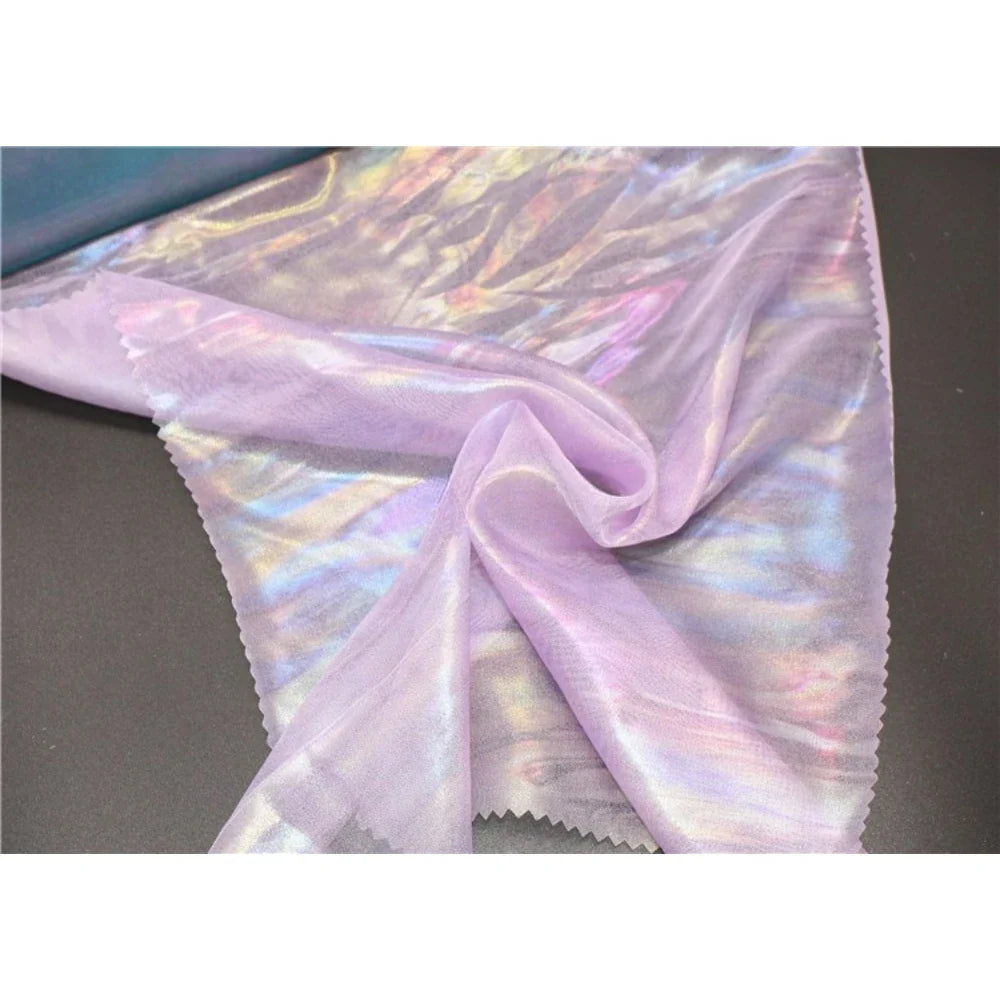 La mousseline irisée violet clair de Longan Craft France - un tissu métallique en polyester vendu au mètre - apporte de l'élégance aux projets de bricolage, sa surface brillante se détachant joliment sur une toile de fond sombre.