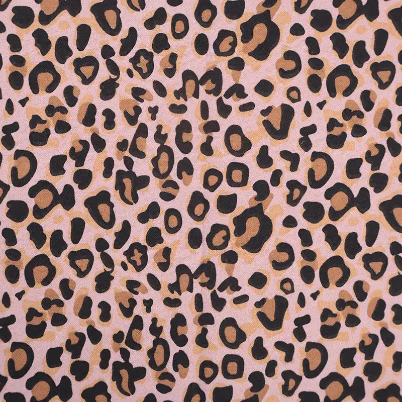 Gros plan sur la Flanelle de coton léopard au mètre de Longon Craft France, montrant des taches noires et brunes sur une flanelle rose pâle - un textile audacieux et confortable idéal pour les peignoirs, les blouses et les chemises.
