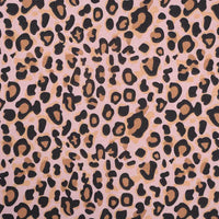 Gros plan sur la Flanelle de coton léopard au mètre de Longon Craft France, montrant des taches noires et brunes sur une flanelle rose pâle - un textile audacieux et confortable idéal pour les peignoirs, les blouses et les chemises.