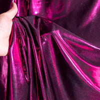 Une main présente le Lamé métallique liquide au mètre de Longan Craft France, un lamé vintage brillant et extensible avec une finition magenta brillante, idéal pour les costumes, les robes de soirée et la couture grâce à sa texture réfléchissante et chatoyante.