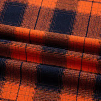 Gros plan sur la Flanelle de coton à carreaux au mètre Longon Craft France, montrant les lignes orange et bleu foncé de ce tissu flanelle confortable, parfait pour chemises, robes ou pantalons d'automne.