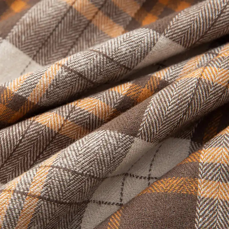 Un gros plan de la flanelle de coton à carreaux au mètre de Longon Craft France montre son motif tissé marron, beige et orange-parfait pour des chemises, robes ou pantalons d'automne confortables grâce à sa texture douce et chaleureuse.