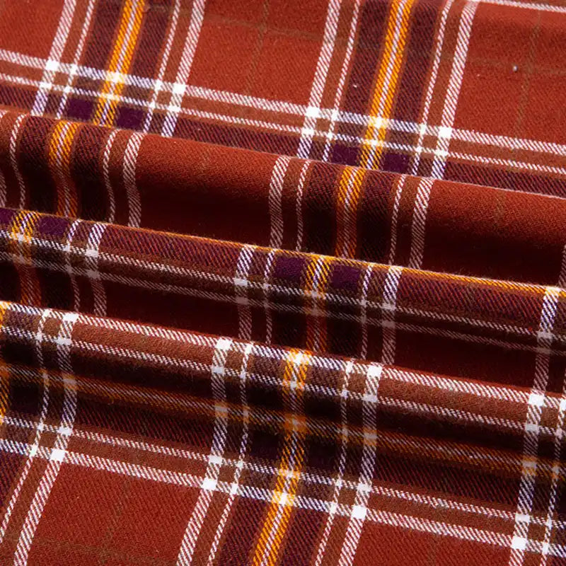 Un gros plan de la Flanelle de coton à carreaux au mètre de Longon Craft France révèle des plis douillets à motifs écossais en rouge, blanc, jaune et noir - un tissu flanelle parfait pour les chemises, les robes ou les pantalons d'automne.