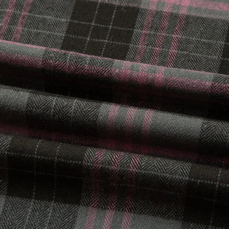 Un gros plan de la Flanelle de coton à carreaux au mètre de Longon Craft France montre son plaid noir et gris avec de fines rayures roses, mettant en valeur la texture confortable de la flanelle, idéale pour les chemises, les robes et les pantalons d'automne.