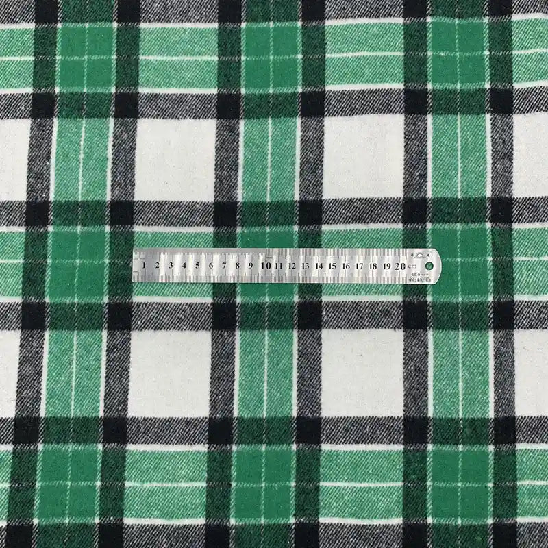 Une règle métallique de 20 cm est posée sur le tissu écossais en polyester-coton vert, noir et blanc de Longon Craft France, vendu au mètre et idéal pour les tenues d'automne, les robes, les chemises ou les projets de couture.