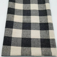 Un morceau de Tissu flanelle à carreaux au mètre de Longon Craft France, présentant un motif à carreaux noir, blanc et gris, est posé à plat sur une surface blanche - une flanelle polyester-coton parfaite pour les projets de couture festifs.