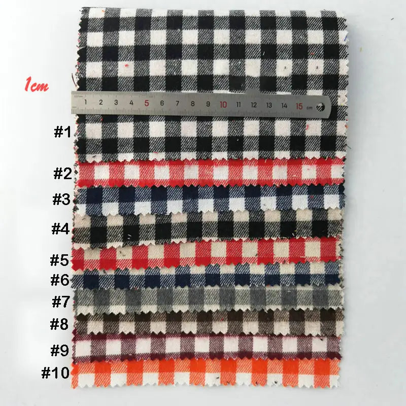 Dix échantillons numérotés de Tissu flanelle à carreaux au mètre de Longon Craft France, une flanelle colorée et douillette en polyester-coton pour la couture festive, sont empilés à côté d'une règle de 1 cm, parfaite pour les projets de textile d'ameublement.