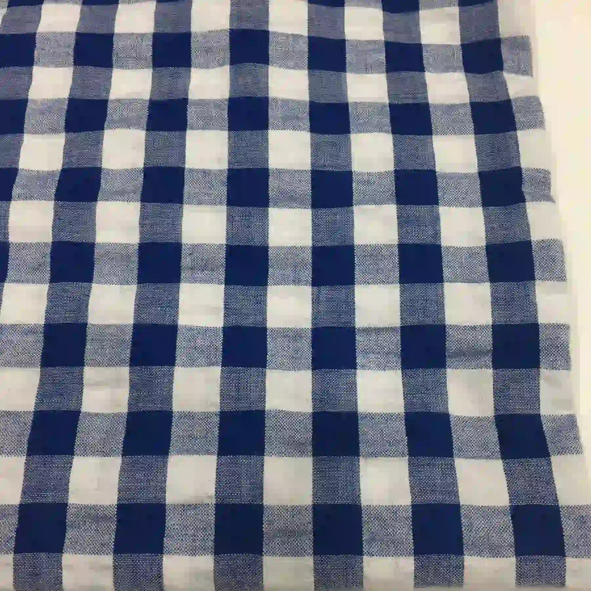 Le Tissu seersucker à carreaux au mètre de Longan Craft France est un tissu léger à motif vichy bleu et blanc, idéal pour vêtements d'été, avec une texture gaufrée visible et des carreaux réguliers.