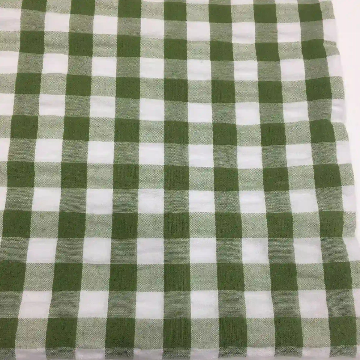 Un carré de Tissu seersucker à motif vichy de Longan Craft France à carreaux verts et blancs est posé à plat. Ce tissu léger à motifs quadrillés est parfait pour les vêtements d'été.