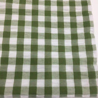 Un carré de Tissu seersucker à motif vichy de Longan Craft France à carreaux verts et blancs est posé à plat. Ce tissu léger à motifs quadrillés est parfait pour les vêtements d'été.