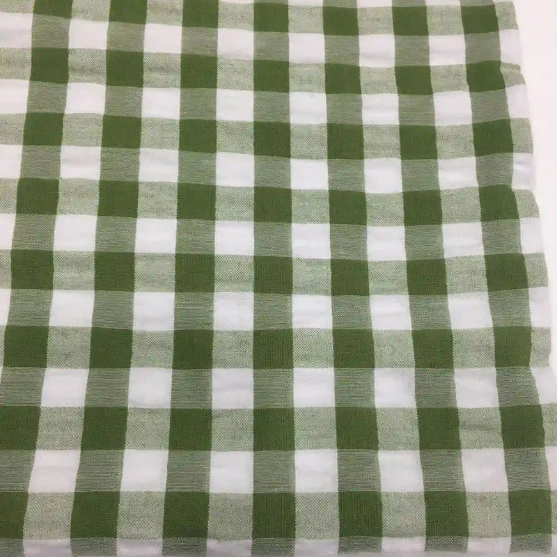 Un carré de Tissu seersucker à motif vichy de Longan Craft France à carreaux verts et blancs est posé à plat. Ce tissu léger à motifs quadrillés est parfait pour les vêtements d'été.
