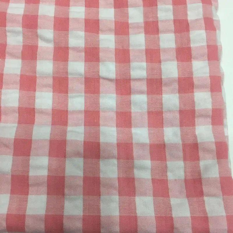 Découvrez le Tissu seersucker à carreaux au mètre de Longan Craft France : un seersucker vichy rose et blanc, léger et légèrement froissé, idéal pour vêtements d'été. Présenté à plat avec des carreaux réguliers.