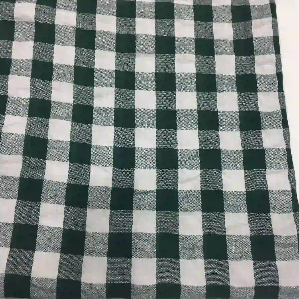 Un gros plan du "Tissu seersucker à carreaux au mètre" de Longan Craft France montre son motif écossais vichy noir et blanc avec des carrés régulièrement espacés en tissu seersucker texturé.