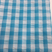 Découvrez le tissu seersucker à carreaux au mètre de Longan Craft France : un motif vichy bleu et blanc, léger et respirant, parfait pour vos vêtements d'été.