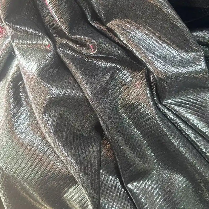 Gros plan sur le tissu lamé plissé argenté brillant de Longan Craft France. Ce tissu polyester extensible aux plis visibles reflète magnifiquement la lumière - idéal pour la couture, les robes DIY et l'artisanat. Disponible au mètre.