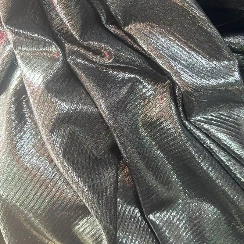 Gros plan sur le tissu lamé plissé argenté brillant de Longan Craft France. Ce tissu polyester extensible aux plis visibles reflète magnifiquement la lumière - idéal pour la couture, les robes DIY et l'artisanat. Disponible au mètre.