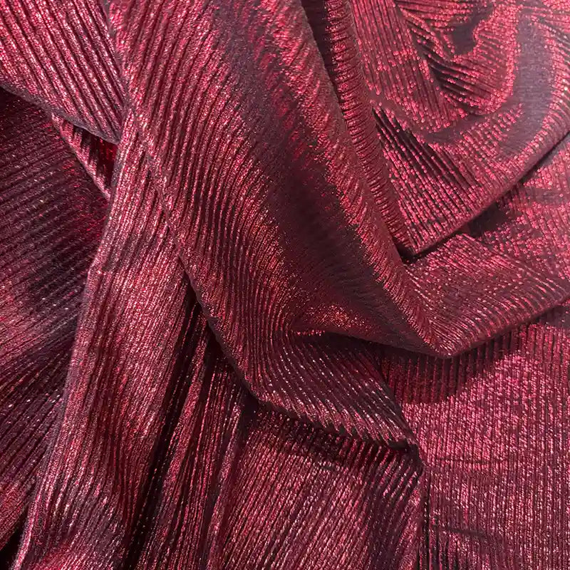 Gros plan sur le Tissu lamé plissé au mètre de Longan Craft France, un textile de polyester rouge brillant aux reflets métalliques et aux plis diagonaux, idéal pour la couture, les robes DIY et l'artisanat.