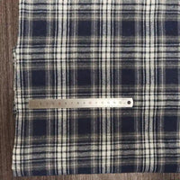 Un morceau de Tissu flanelle à carreaux polyester-coton au mètre de Longon Craft France est posé sur une surface en bois, avec une règle métallique de 20 cm placée en travers pour montrer l'échelle. Idéal pour les projets de couture d'automne et de vêtements pour bébés.
