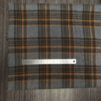 Une règle métallique de 15 cm est posée sur le tissu flanelle à carreaux polyester-coton au mètre de Longon Craft France. Ce tissu à carreaux jaune et noir est idéal pour la couture d'automne ou les vêtements de bébé.