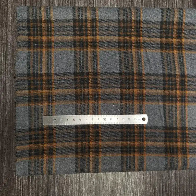 Une règle métallique de 15 cm est posée sur le tissu flanelle à carreaux polyester-coton au mètre de Longon Craft France. Ce tissu à carreaux jaune et noir est idéal pour la couture d'automne ou les vêtements de bébé.