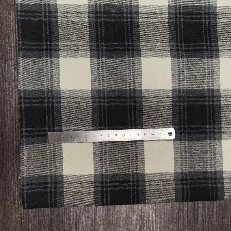 A tissu flanelle à carreaux polyester-coton Longon Craft France, en noir, blanc et gris, est posé sur du bois. Un mètre ruban montre 16 cm-idéal pour la couture de vêtements bébé ou l'automne.