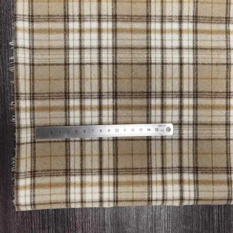 Le Tissu flanelle à carreaux polyester-coton au mètre de Longon Craft France, matière confortable pour l'automne et idéale pour vêtements bébé, est présenté sur bois foncé avec une règle de 20 cm posée dessus.