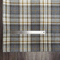 Une règle métallique Longon Craft France repose sur un tissu polyester-coton flanelle à carreaux, idéal pour la couture d'automne ou de vêtements de bébé, mesurant de 1 à 15 cm sur une surface en bois.