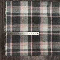 Une règle en métal de 20 cm repose sur le tissu flanelle à carreaux polyester-coton de Longon Craft France, qui présente des rayures noires, blanches et roses - parfaites pour les vêtements d'automne ou la couture des bébés - sur une surface texturée.