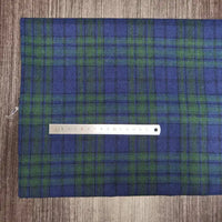 Une règle métallique de 15 cm repose sur le tissu écossais en flanelle de polyester-coton de Longon Craft France, un textile d'automne confortable idéal pour les vêtements de bébé, présenté sur une surface en bois.
