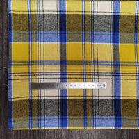 Un morceau de Longon Craft France Tissu flanelle à carreaux polyester-coton est posé à plat sur une surface sombre, avec une règle métallique en centimètres placée horizontalement en travers du confortable tissu d'automne pour vêtements de bébé.