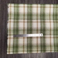 Un tissu flanelle à carreaux vert, beige et blanc en polyester-coton de Longon Craft France est posé à plat sur du bois foncé, avec une règle métallique de 20 cm placée horizontalement près du bord inférieur pour indiquer la taille du tissu.