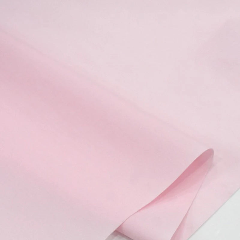 Un gros plan du Popeline polyester-coton au mètre de Longan Craft France montre sa texture douce et pastel. Ce doux et respirant tissu popeline uni à armure toile est parfait pour les peignoirs, chemises et langes.