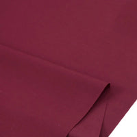 Un morceau de Popeline marron en polyester-coton au mètre de Longan Craft France est présenté sur un fond uni. Ce tissu lisse et mat est doux et respirant, ce qui le rend idéal pour les peignoirs, les chemises et les langes.