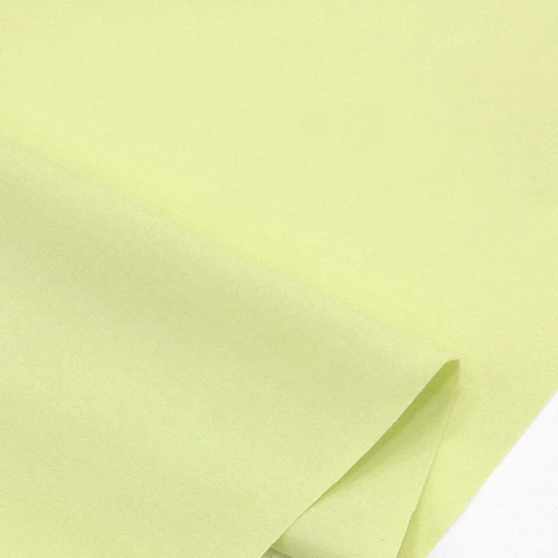 Gros plan sur des feuilles superposées de Popeline polyester-coton au mètre de Longan Craft France, un doux et respirant tissu popeline uni à armure toile, parfait pour les peignoirs, chemises et langes.