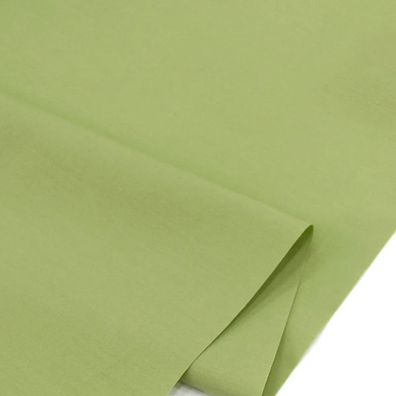 Un gros plan du Popeline polyester-coton au mètre de Longan Craft France montre sa texture lisse et vert clair. Ce tissu popeline doux et respirant à armure toile est idéal pour les peignoirs, les chemises et les couches grâce à sa durabilité.
