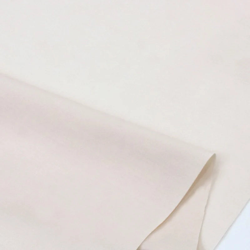 Gros plan sur Popeline polyester-coton au mètre de Longan Craft France, un tissu popeline uni, lisse et respirant, partiellement plié à un coin et présenté sur une surface plane, idéal pour les peignoirs, les chemises et les nappes.