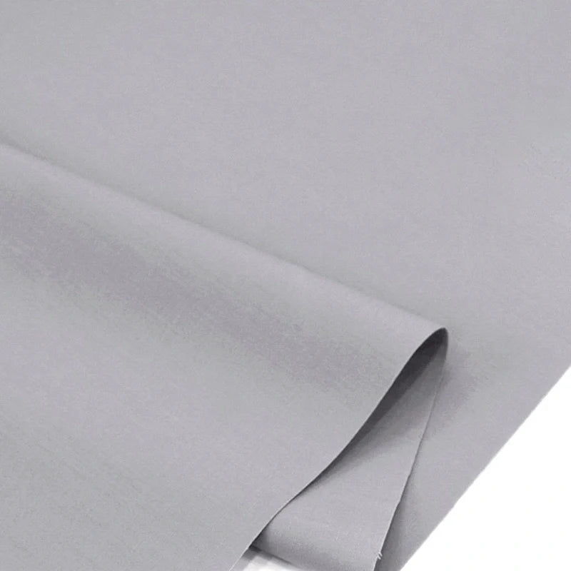 Gros plan sur Popeline polyester-coton au mètre de Longan Craft France, un doux et respirant tissu uni à armure toile, léger gris, parfait pour robes, chemises ou nappes et idéal pour vêtements ou décoration intérieure.