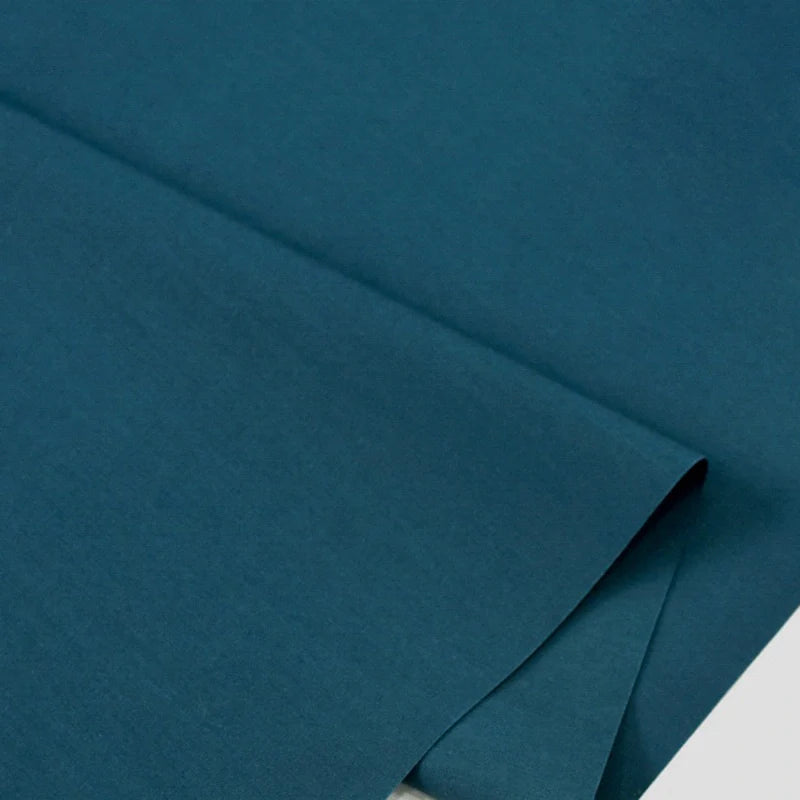 Gros plan sur Popeline polyester-coton au mètre de Longan Craft France, un doux et respirant tissu popeline uni à armure toile, soigneusement plié-idéal pour les peignoirs, chemises ou nappes et divers projets de couture.