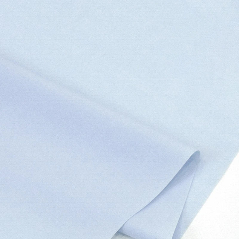 Gros plan sur Popeline polyester-coton au mètre de Longan Craft France, un tissu popeline uni à armure toile doux et respirant, partiellement plié pour montrer sa texture lisse et durable - idéal pour les peignoirs, chemises et langes.